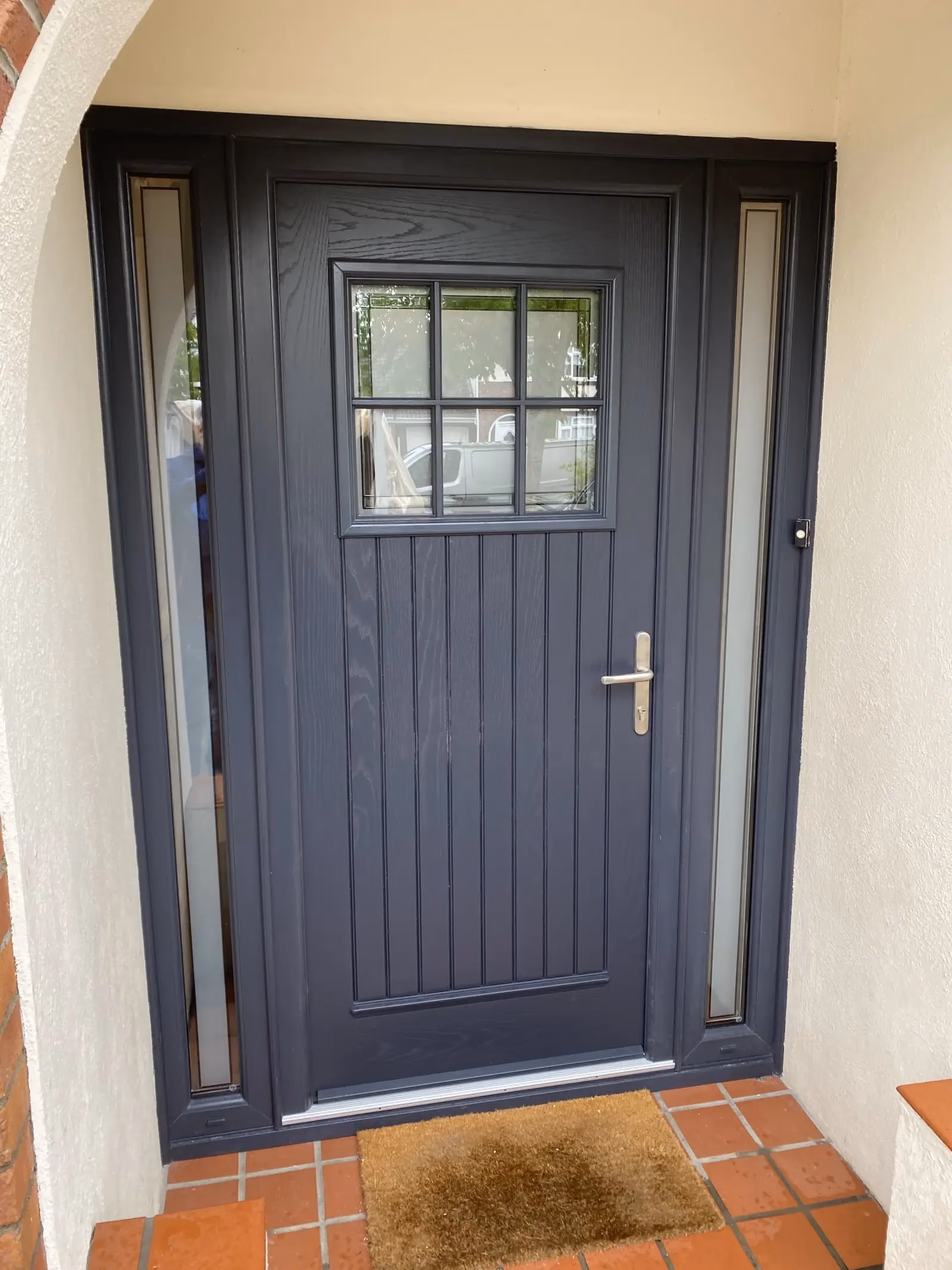 Close detail of a composite front door with matte black hardware and brushed letterplate