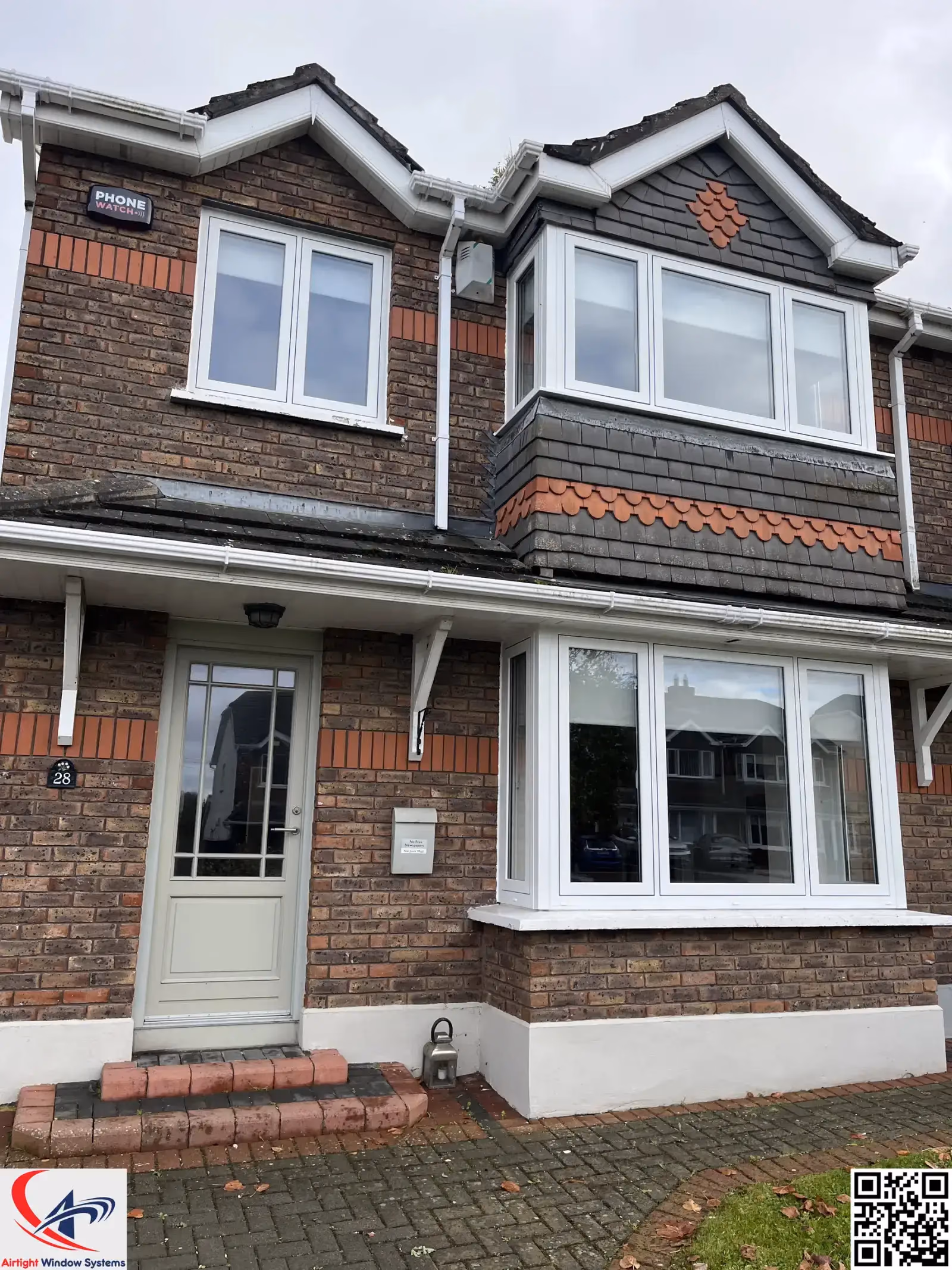 Black composite door and white uPVC bay window on a brick bungalow