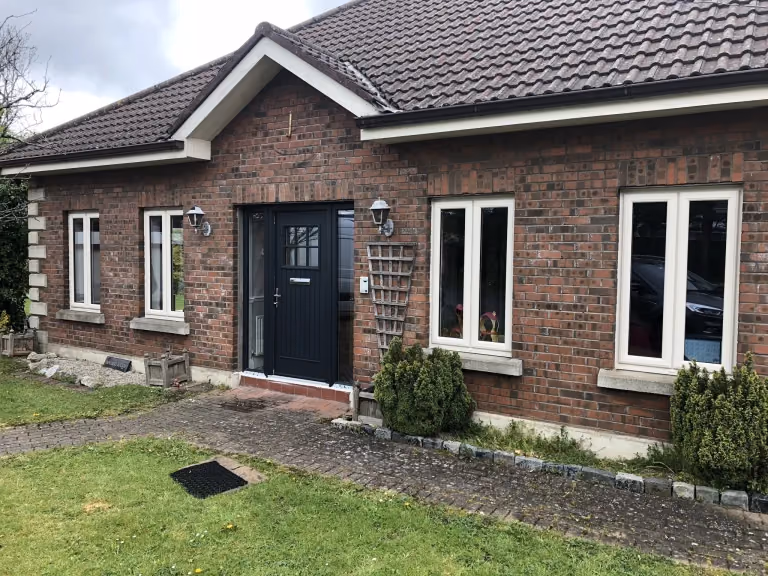 Black composite front door and cream uPVC windows on a brick bungalow